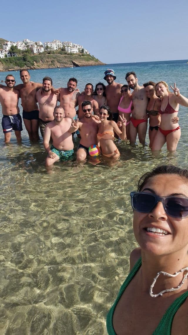 Eine WeRoad-Gruppe macht an einem sonnigen Tag ein Selfie im klaren, seichten Meerwasser.
