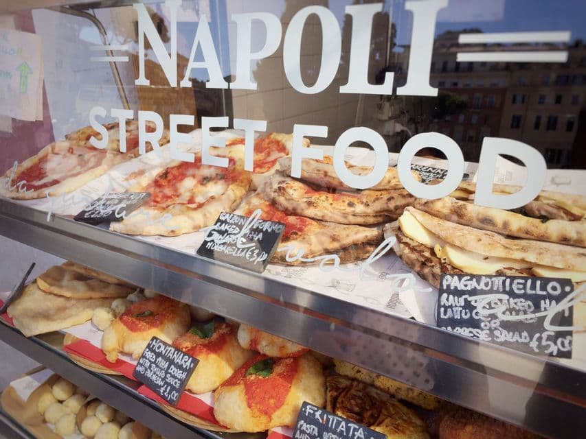 Eine Schaufensterauslage mit verschiedenen italienischen Streetfoods wie Pizza und Calzones, mit der Aufschrift 'Napoli Street Food' auf dem Glas.
