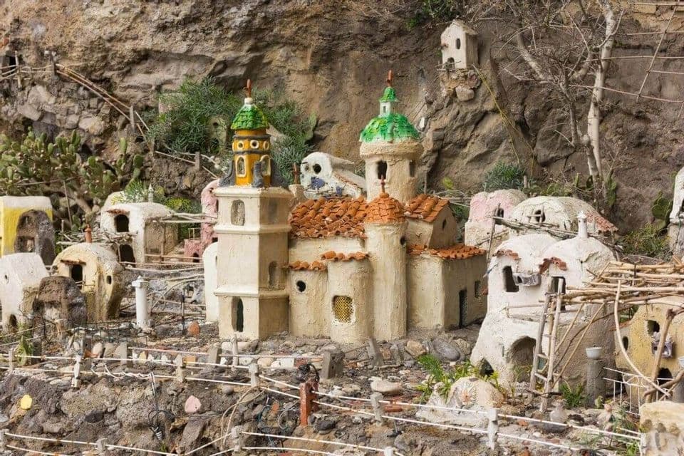 Un modelo en miniatura hecho a mano de un pueblo, que incluye una iglesia con cúpulas coloridas, construido en la ladera de un acantilado rocoso.