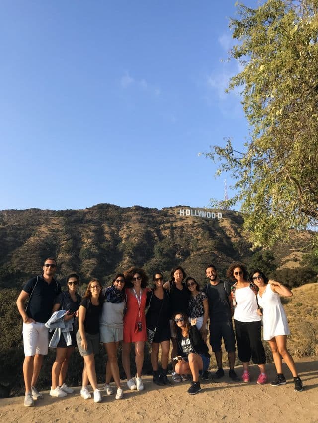 Eine WeRoad-Gruppe posiert an einem sonnigen Tag auf einem Hügel vor dem Hollywood-Schriftzug für ein Foto.