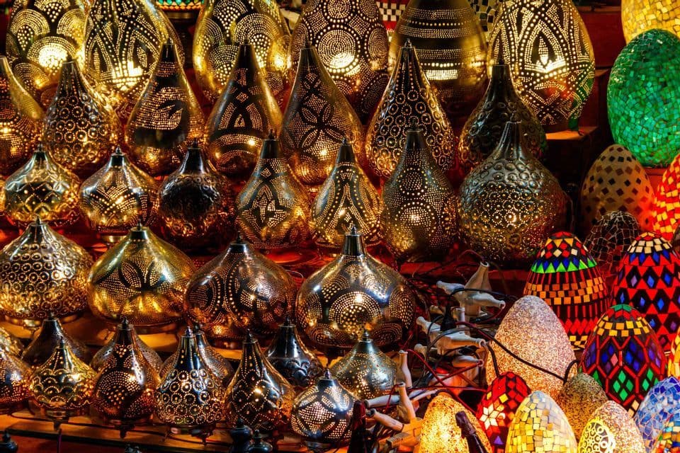 Una ricca esposizione di lampade illuminate e finemente decorate, con dettagli in metallo traforato e mosaici di vetro colorato.