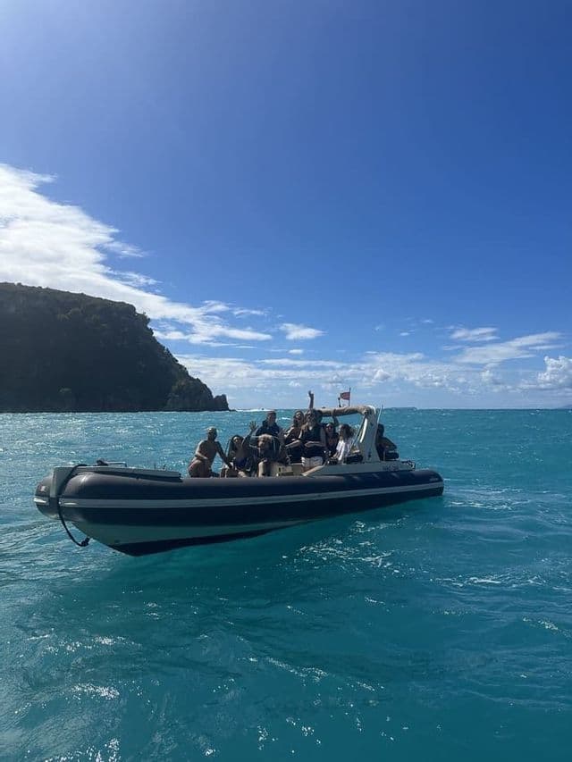 Un gruppo WeRoad in viaggio che posa e sorride su un gommone nel mare turchese sotto un cielo blu.