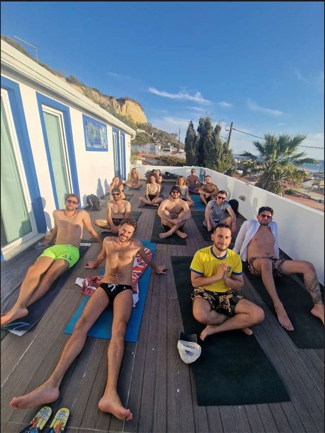 Un viaggio di gruppo WeRoad con pratica yoga su tappetini stesi su una terrazza panoramica soleggiata e un deck in legno.