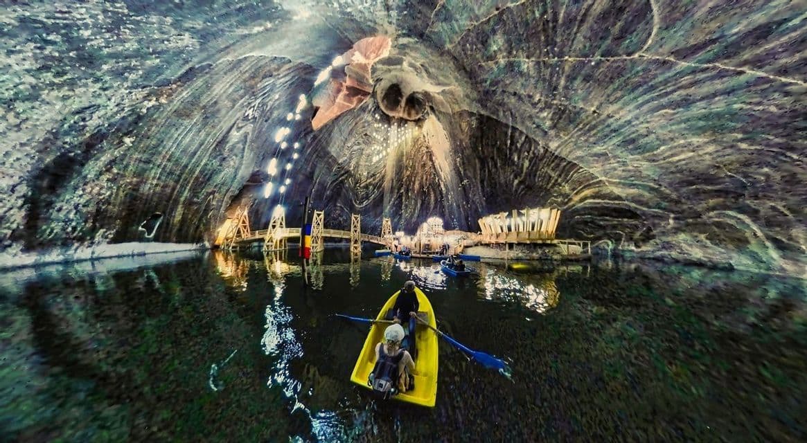 Un gruppo WeRoad rema in barca su un lago all'interno di una vasta e illuminata grotta di sale sotterranea.