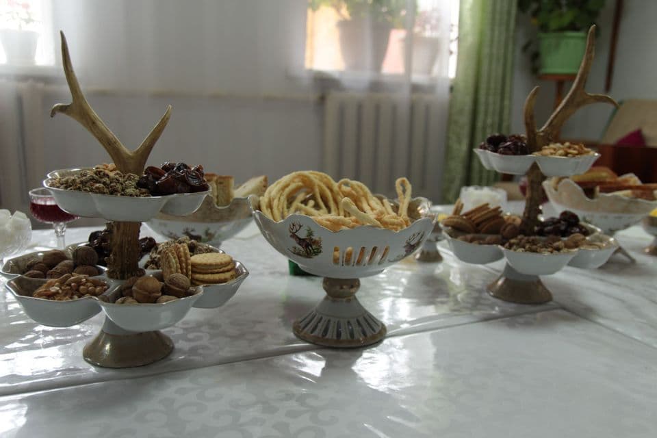 Présentoirs étagés ornés de bois de cerf, garnis de diverses noix, dattes et biscuits, sur une table à manger.