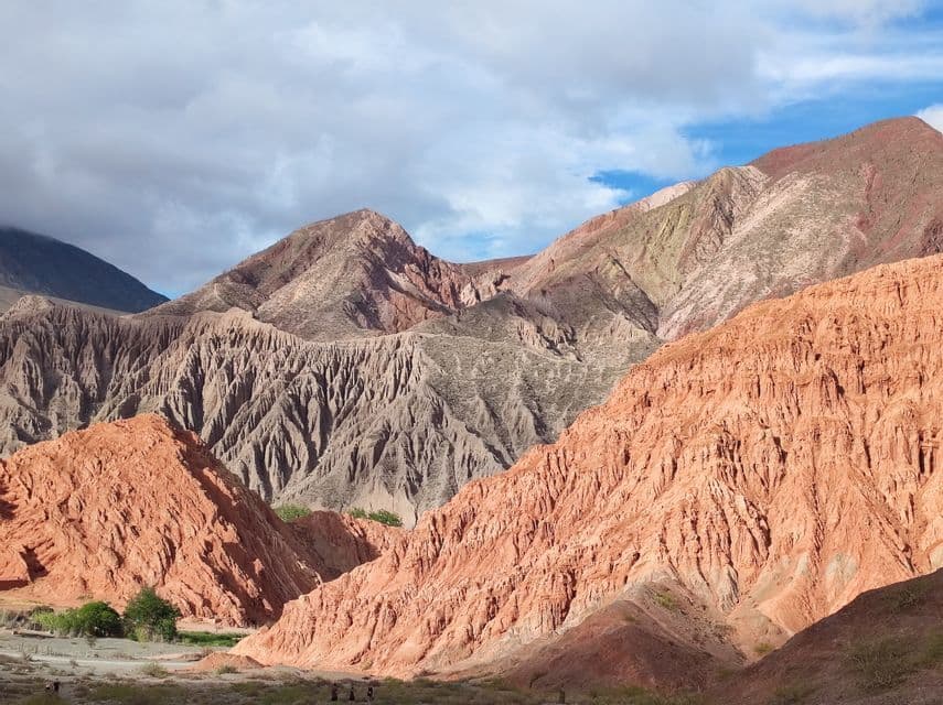 Montagne colorate ed erose, nelle sfumature del rosso e del marrone, dominano una valle dove un piccolo gruppo WeRoad sta camminando.