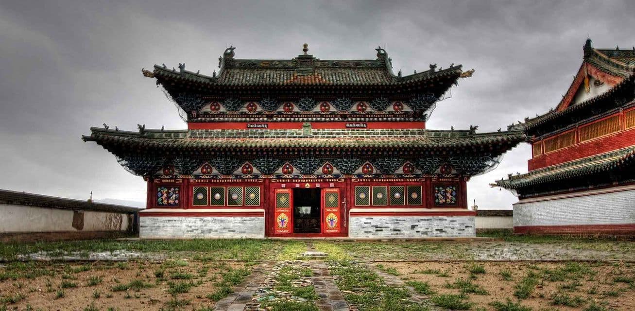 Un tempio tradizionale dell'Asia orientale con tetto in tegole verdi e pareti rosse si erge in un cortile sotto un cielo coperto.