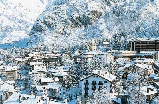 Un villaggio alpino innevato con chalet tradizionali incastonato ai piedi di un'enorme montagna coperta di neve.