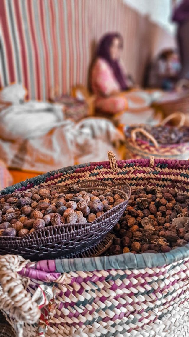 Nahaufnahme von farbenfrohen geflochtenen Körben, gefüllt mit ganzen Nüssen, mit einer Person im unscharfen Hintergrund.