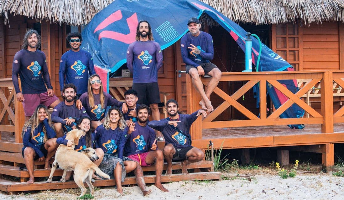 Un viaggio di gruppo WeRoad con magliette abbinate in posa con un cane sul portico di una capanna di legno sulla spiaggia.