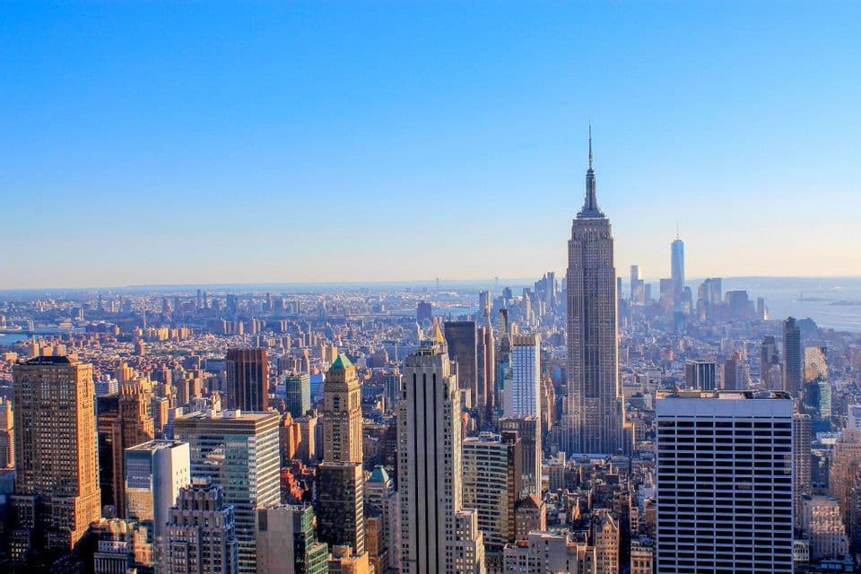 Eine Luftaufnahme der New Yorker Skyline, mit dem Empire State Building prominent unter klarem blauem Himmel.