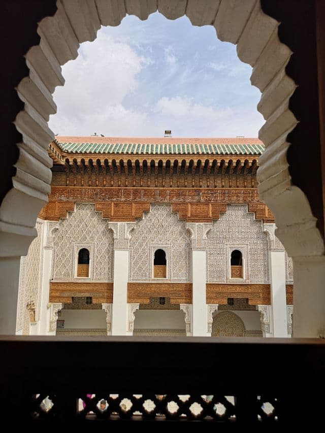 Ein verziertes Gebäude mit detaillierten Schnitzereien und einem grün gekachelten Dach, durch einen bogenförmigen Durchgang gesehen.