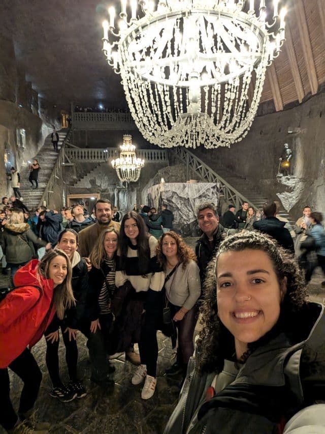 Un viaje en grupo de WeRoad se toma una selfie en una gran caverna con paredes de roca decorada con candelabros de cristal ornamentados.