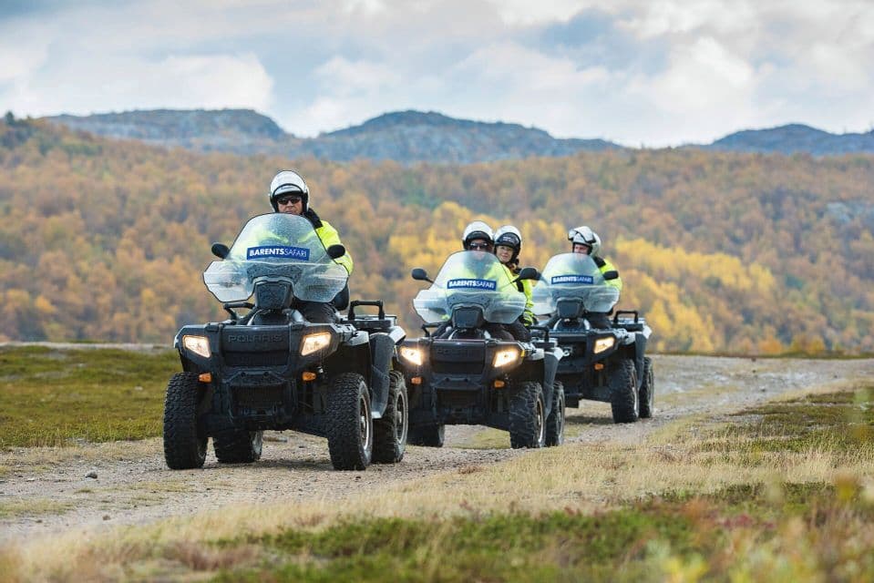 Un viaggio di gruppo WeRoad in quad, in fila su una strada sterrata, attraverso un paesaggio collinare con foliage autunnale.