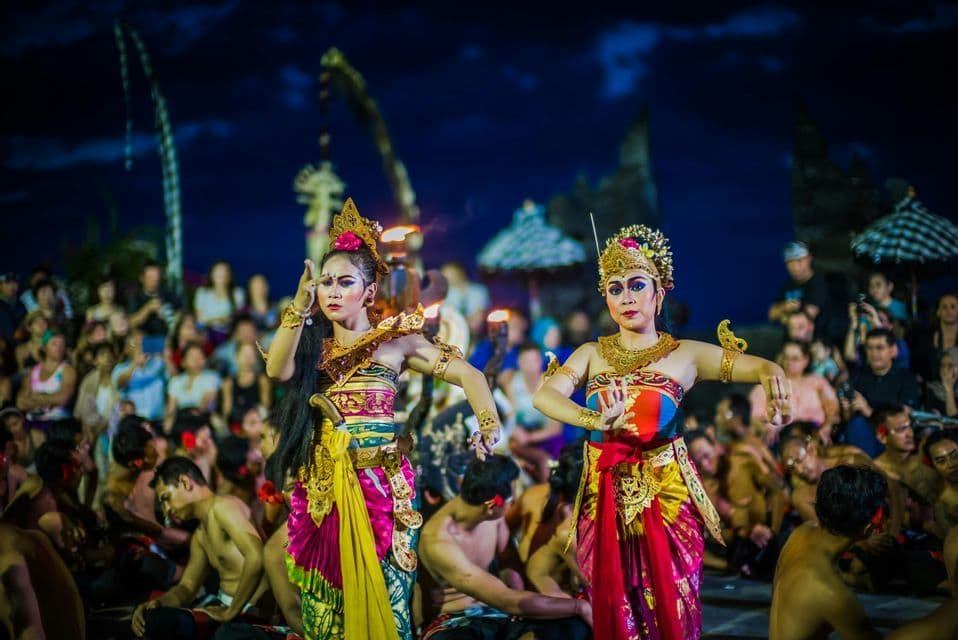 Due donne in elaborati costumi tradizionali e copricapi eseguono una danza culturale per un pubblico di notte.