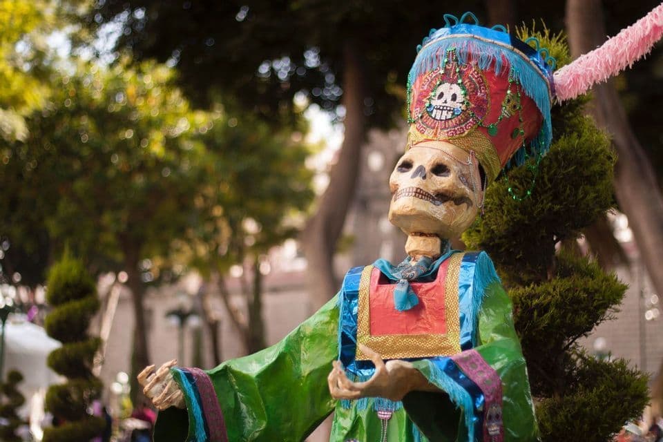 Una figura de esqueleto decorativa con un traje colorido y un elaborado tocado para una celebración del Día de Muertos.