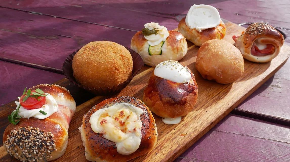 Una varietà di pasticcini salati e stuzzichini fritti italiani, esposti su un tagliere di legno su un tavolo viola.