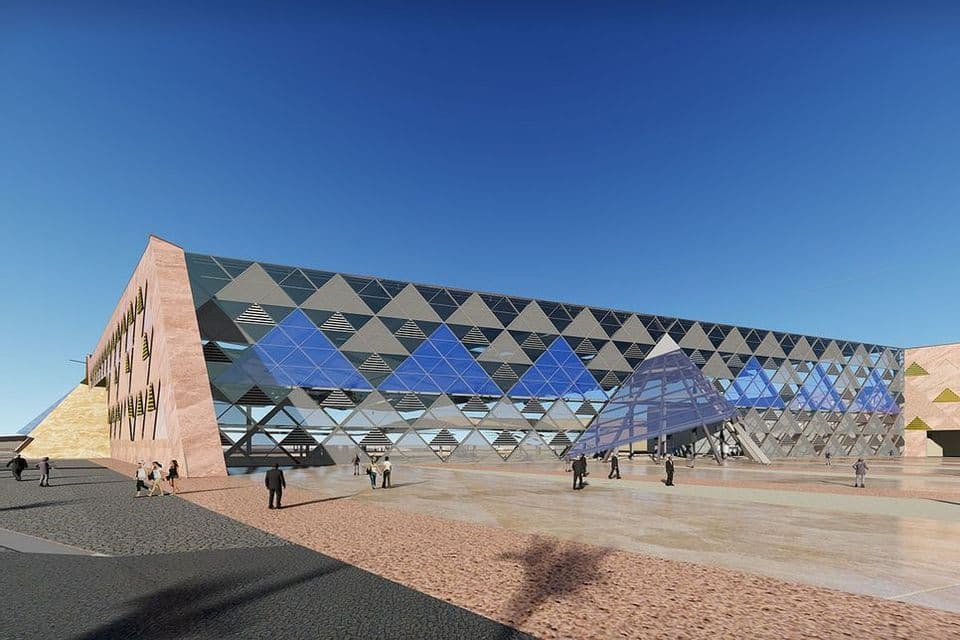 Una representación arquitectónica de un edificio grande y moderno con una fachada geométrica de paneles de vidrio triangulares bajo un cielo azul claro.