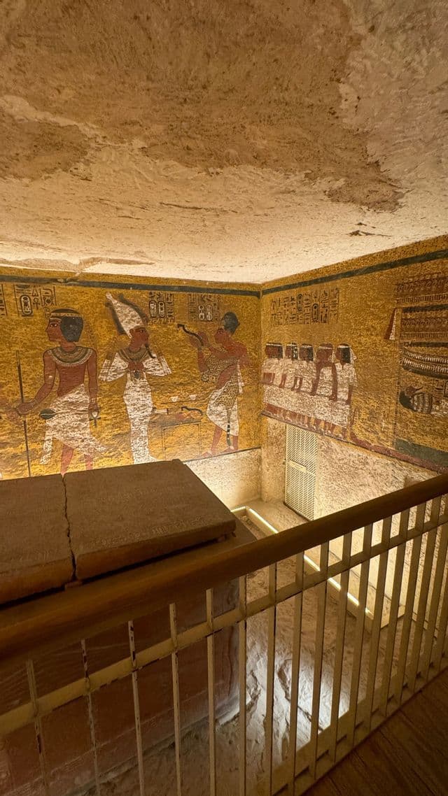 Blick von einem Gang in ein altes ägyptisches Grab mit einem Steinsarkophag und mit gemalten Hieroglyphen bedeckten Wänden