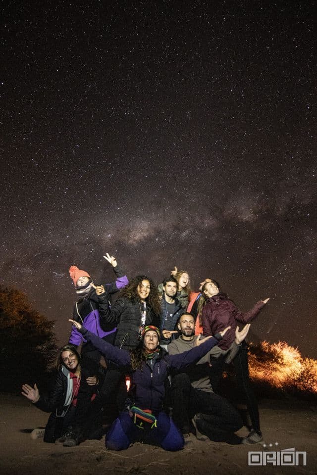 Un grupo de WeRoad se toma una foto bajo un cielo nocturno repleto de estrellas.