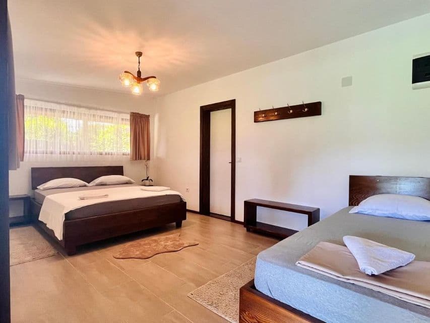 Una camera da letto luminosa con un letto matrimoniale e un letto singolo, entrambi con strutture in legno scuro, su pareti bianche e pulite.