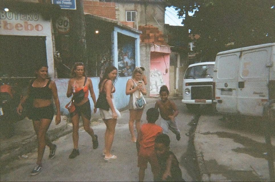 Un viaje en grupo de mujeres de WeRoad caminando por una calle de la ciudad mientras varios niños locales juegan junto a ellas.