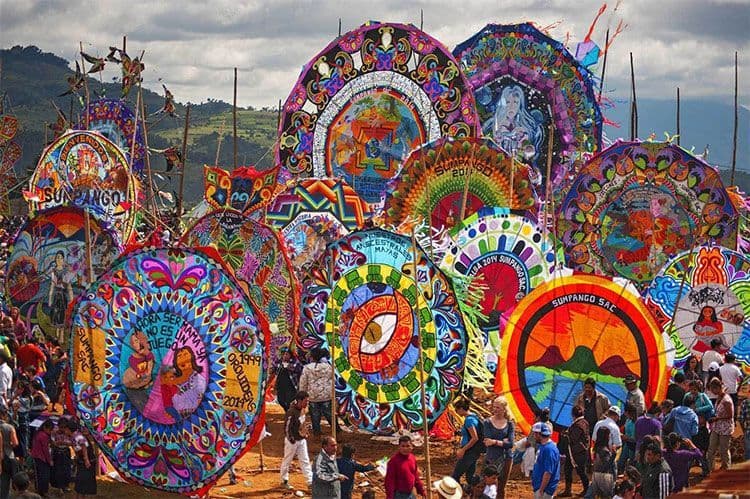 Decine di aquiloni grandi, colorati e riccamente decorati sono esposti in un campo durante un festival all'aperto affollato di persone
