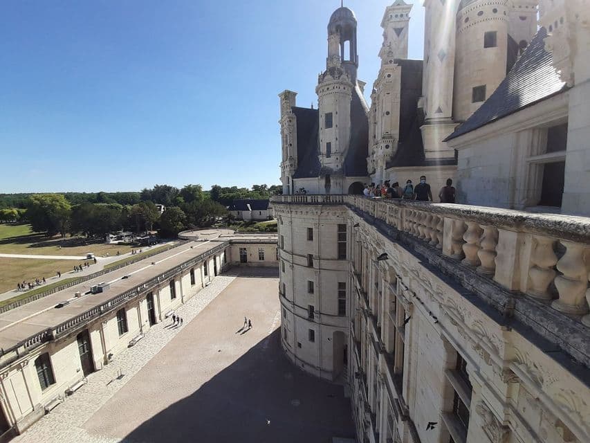 Un groupe WeRoad se tient sur la haute terrasse d'un château en pierre, dominant la cour et les jardins par une journée ensoleillée.