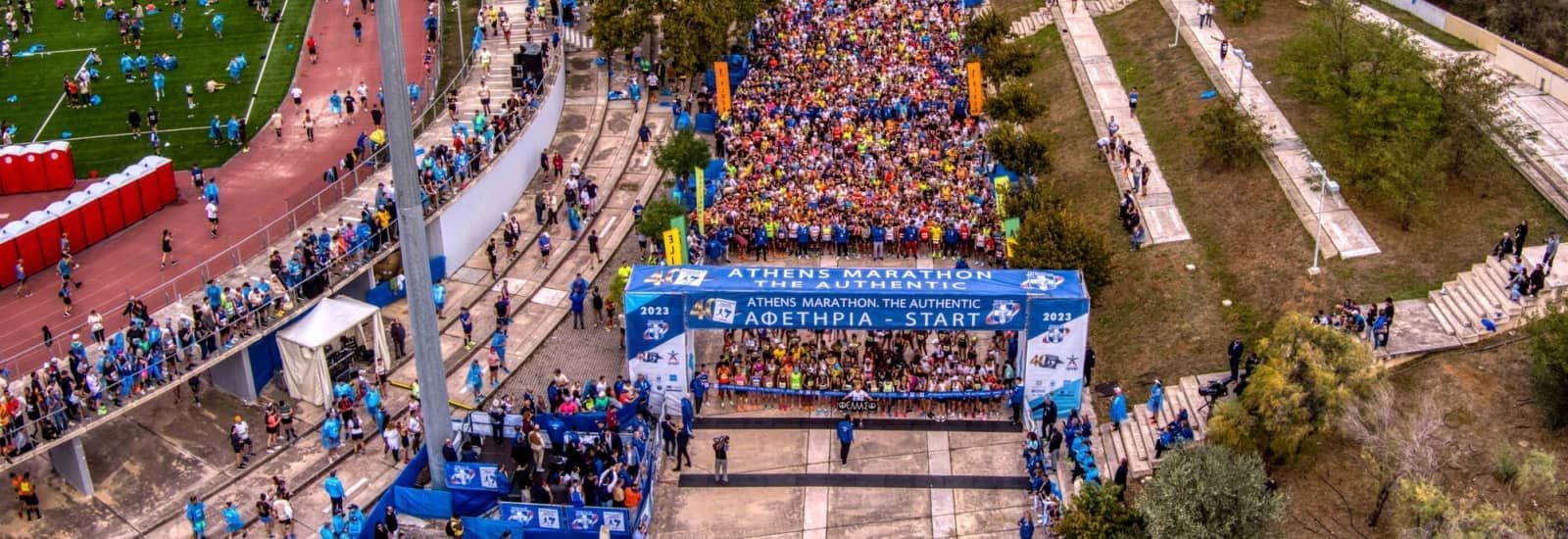 Una vista aerea di una folla immensa di corridori riuniti alla linea di partenza della Maratona di Atene.