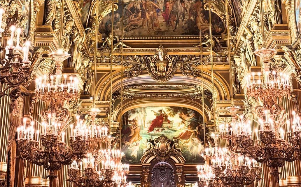 Der prächtige goldene Innenraum eines Opernhauses oder Theaters, mit beleuchteten Kronleuchtern, aufwendigen Schnitzereien und klassischen Gemälden.