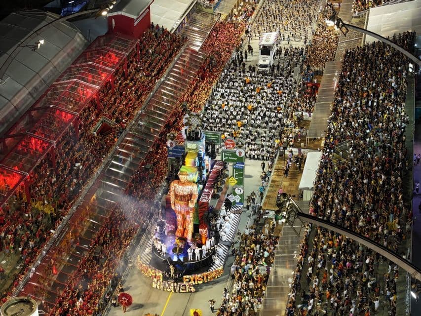 Une vue aérienne d'un grand défilé de carnaval de nuit, avec un char élaboré avançant dans une rue bondée de spectateurs.