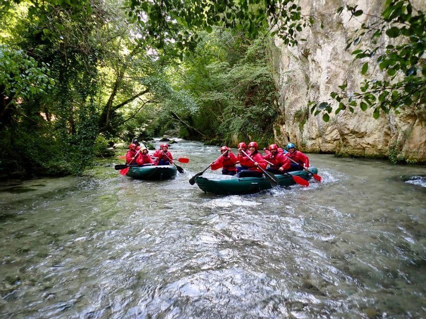 Un gruppo WeRoad scende il fiume in due gommoni, circondato da una lussureggiante foresta e da una scogliera rocciosa.