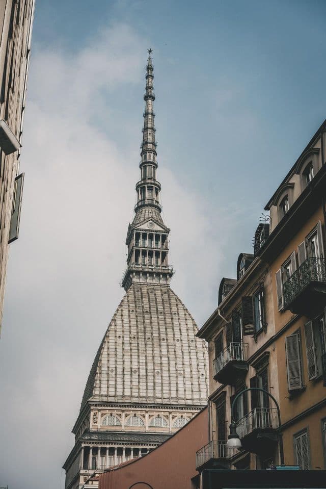 Vista en contrapicado de la gran cúpula y la imponente aguja de un edificio histórico, desde una calle de la ciudad.
