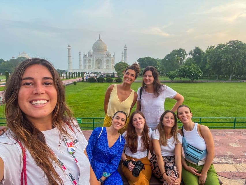 Un grupo de mujeres sonrientes de viaje con WeRoad se toma una selfie frente al Taj Mahal.