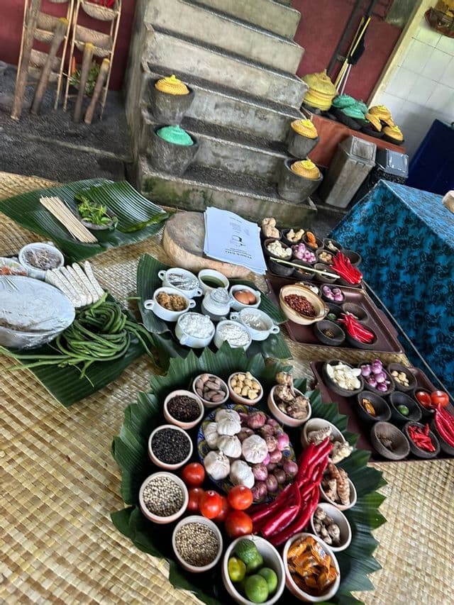 Vue de dessus de légumes frais, herbes et épices disposés dans des bols et sur des feuilles de bananier sur une natte tressée.