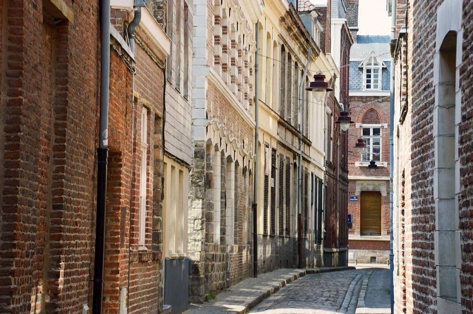 Une vue sur une étroite rue pavée vide bordée de bâtiments résidentiels en briques rouges.