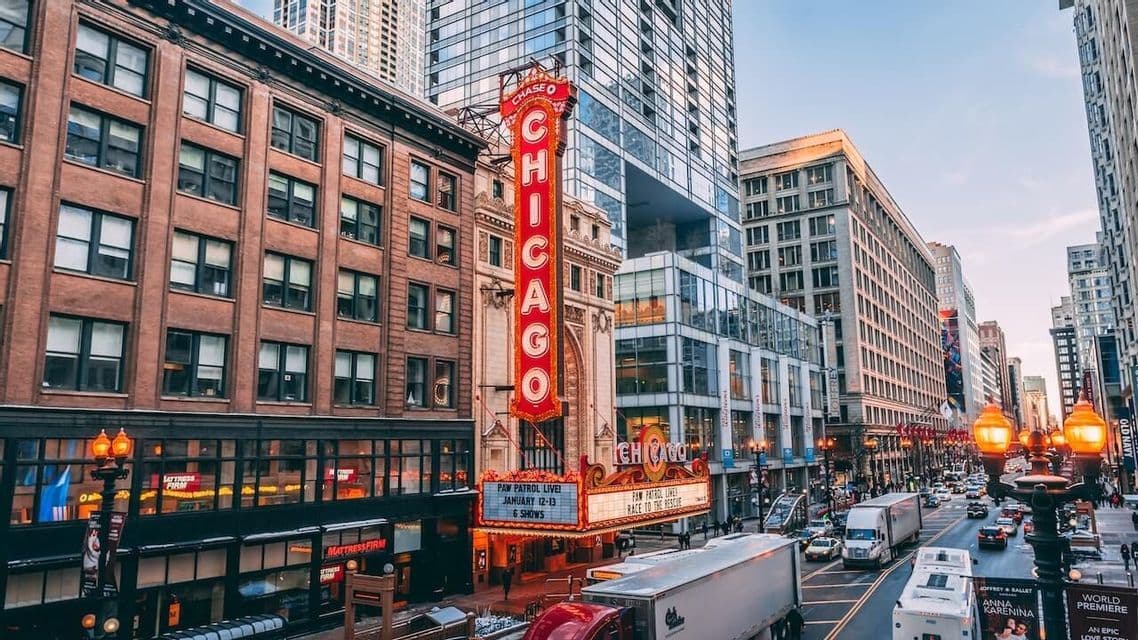 L'insegna verticale illuminata del Chicago Theatre si erge su una trafficata via cittadina con traffico e alti edifici.
