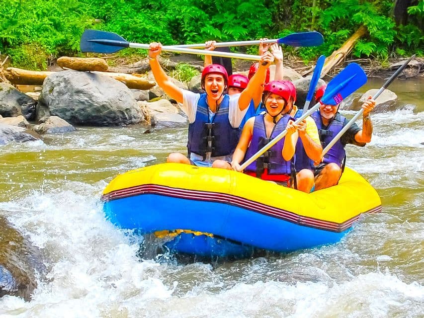 Un voyage de groupe WeRoad en rafting en eaux vives dans un radeau jaune, souriants et pagaies levées en l'air.