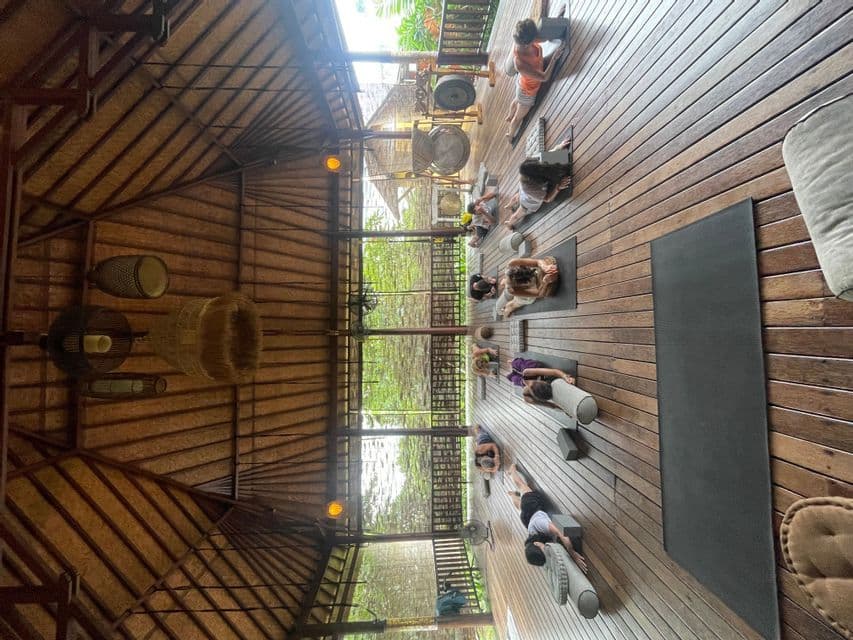 Un viaggio di gruppo WeRoad che pratica yoga su tappetini in uno studio di legno all'aperto con soffitto alto