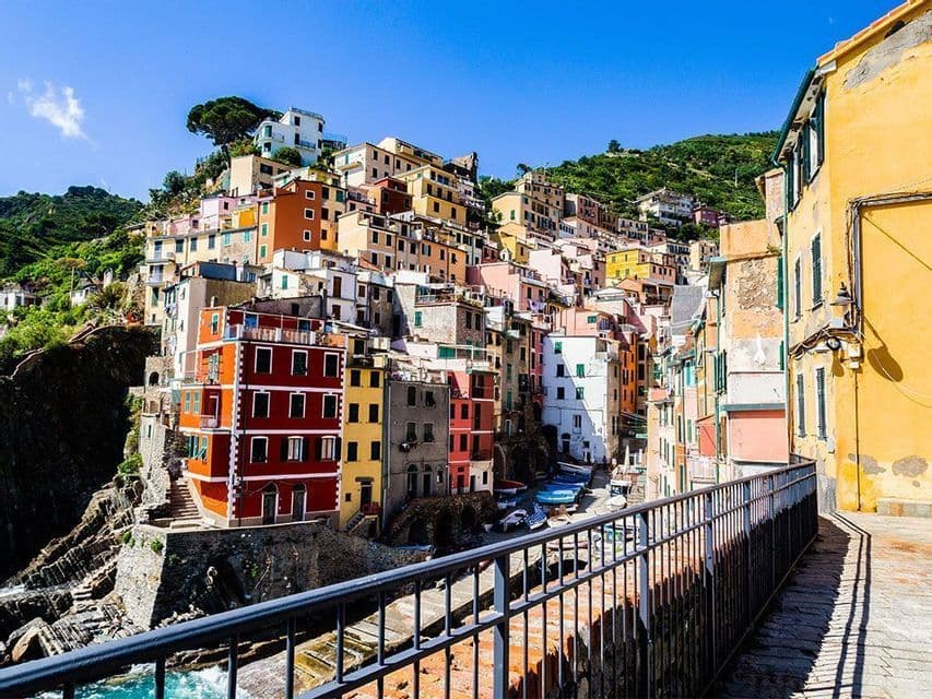 Vista diurna di case colorate incastonate in una ripida scogliera, osservate da una passeggiata sul lungomare.