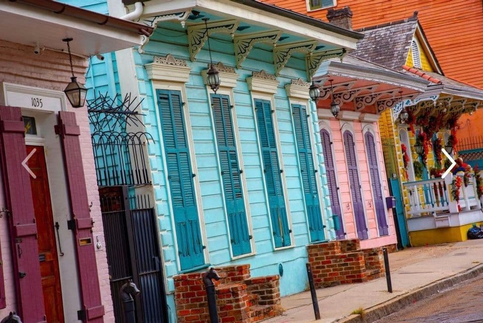 A street lined with colorful houses featuring bright shutters and intricate wooden trim on the eaves.