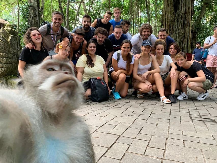 Una scimmia si scatta un selfie ravvicinato con un gruppo WeRoad, sorridendo e posando in una foresta.
