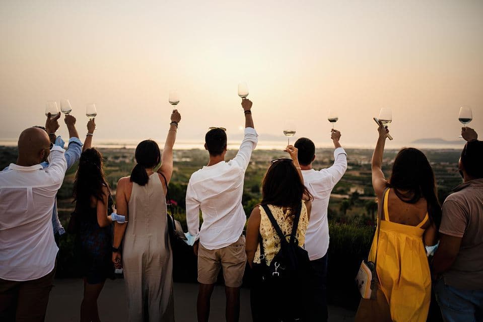 Un gruppo WeRoad alza i calici in un brindisi, ammirando un vasto paesaggio al tramonto.