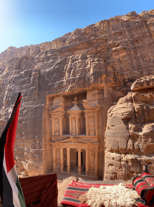 Una vista dall'alto di un'elaborata facciata scolpita in una parete di arenaria, con un tappeto rosso e una bandiera in primo piano.