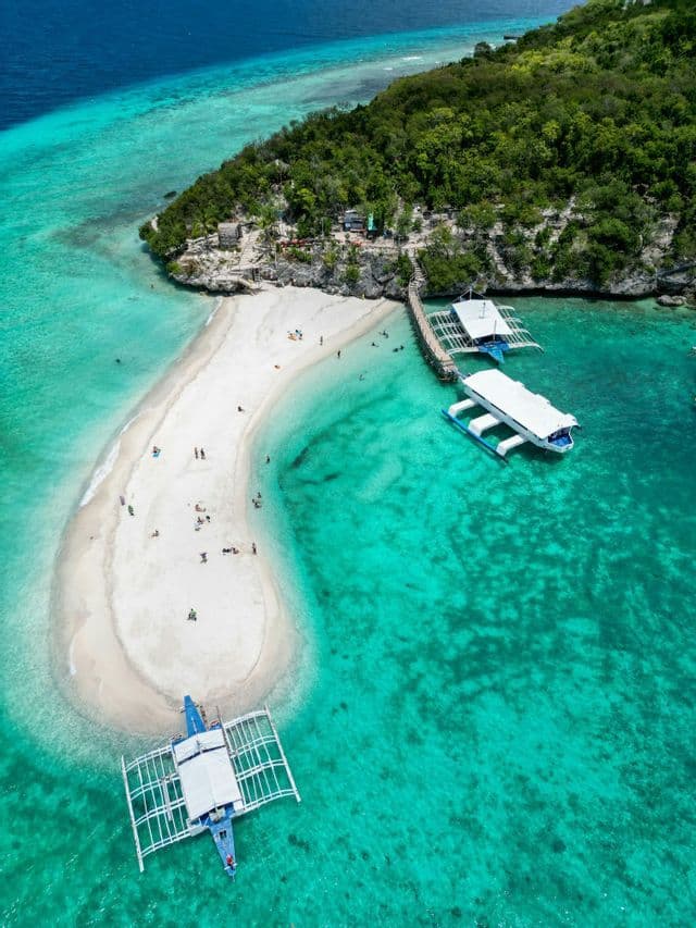 Luftaufnahme einer WeRoad Gruppenreise auf einer weißen Sandbank, umgeben von klarem türkisfarbenem Wasser und traditionellen Booten.