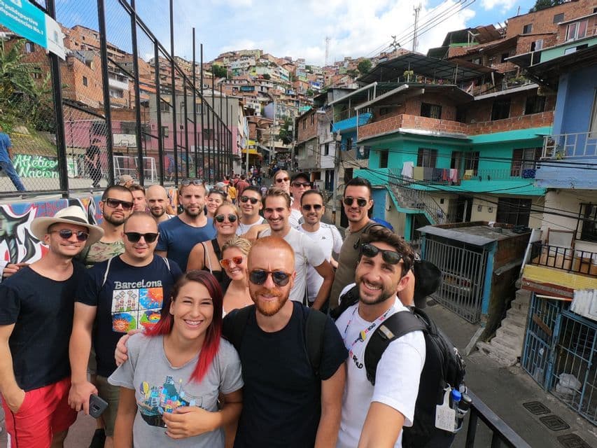 Eine WeRoad-Gruppe macht ein Selfie auf einer Straße vor dem Hintergrund bunter Häuser an einem steilen Hang.