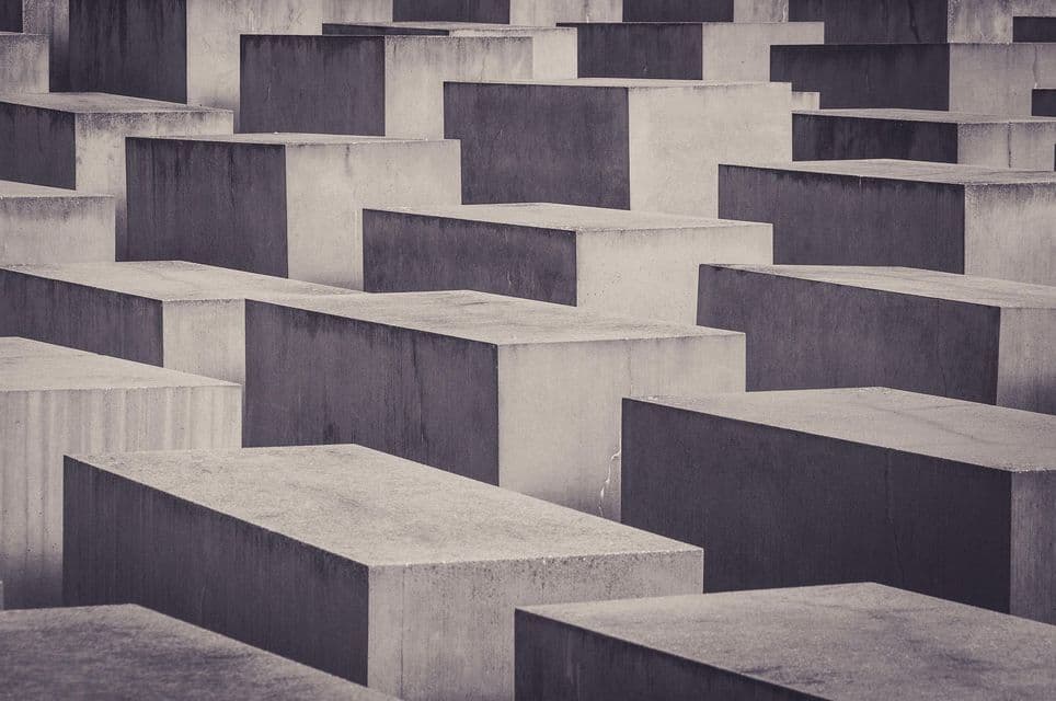 Una vista abstracta y monocromática de numerosos bloques rectangulares de hormigón de distintas alturas, dispuestos en una densa cuadrícula.