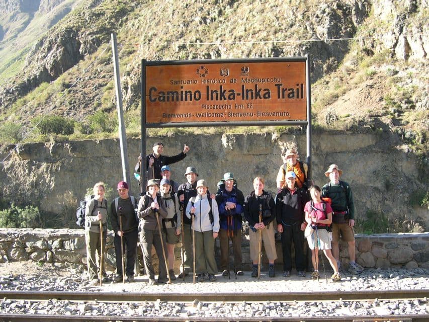 A WeRoad group trip in hiking gear poses for a photo under the 'Camino Inka-Inka Trail' sign before starting their trek.