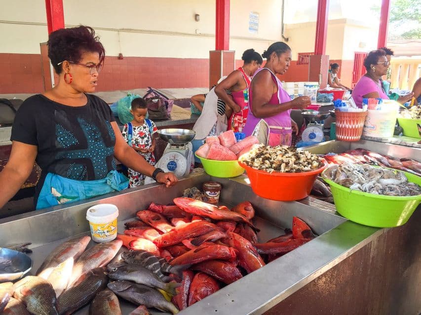 Fischhändlerinnen an einem Fischmarktstand mit frischem Rotfisch und Meeresfrüchten.