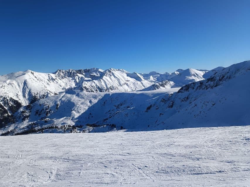 Une vue panoramique sur une chaîne de montagnes enneigée sous un ciel bleu profond et sans nuages, par une journée ensoleillée.